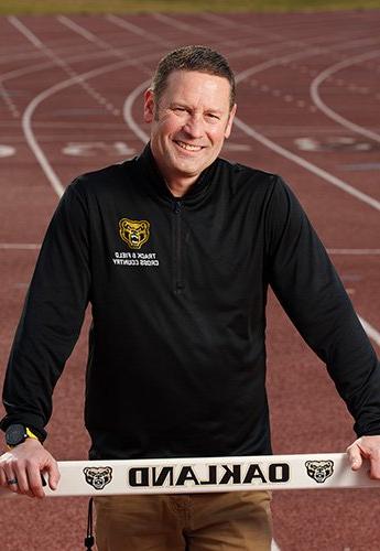 A man standing on the track with a hurdle